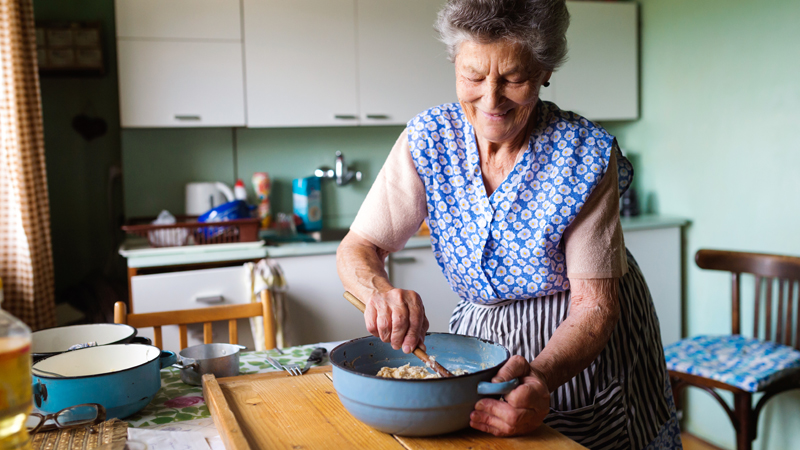 Senhora a preparar comida numa tigela, em cima da mesa da cozinha